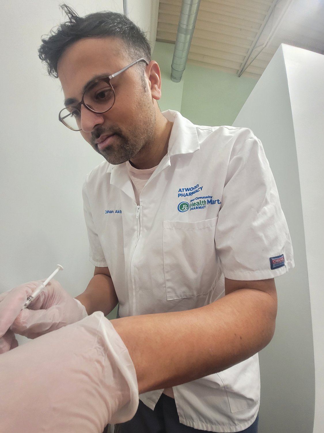 Dr. Zahan Akbar, Pharmacist and owner of Atwood Pharmacy, delivers a booster shot.